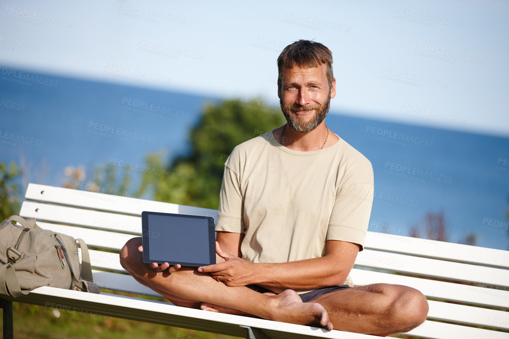 Buy stock photo Happy man, portrait and bench with tablet screen for advertising, marketing or outdoor app. Mature, male person or yogi with smile or technology display for tutorial, health tips or mockup at beach