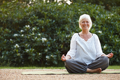 Buy stock photo Portrait of an attractive mature woman sitting in the lotus position outdoors