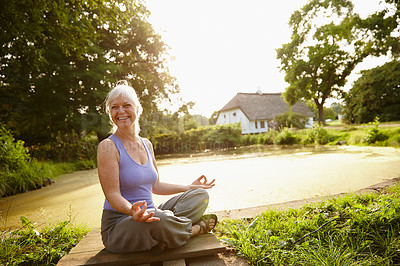 Buy stock photo Shot of an attractive mature woman meditating in a garden at sunset