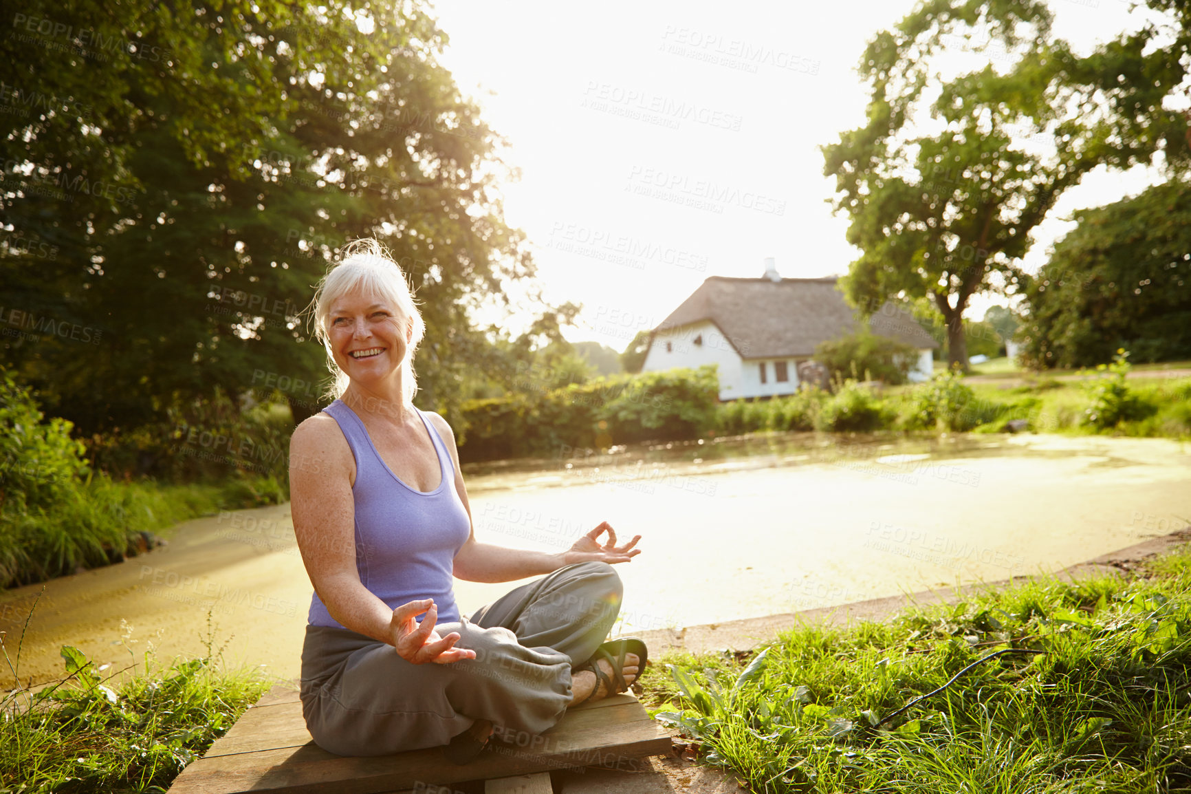 Buy stock photo Shot of an attractive mature woman meditating in a garden at sunset