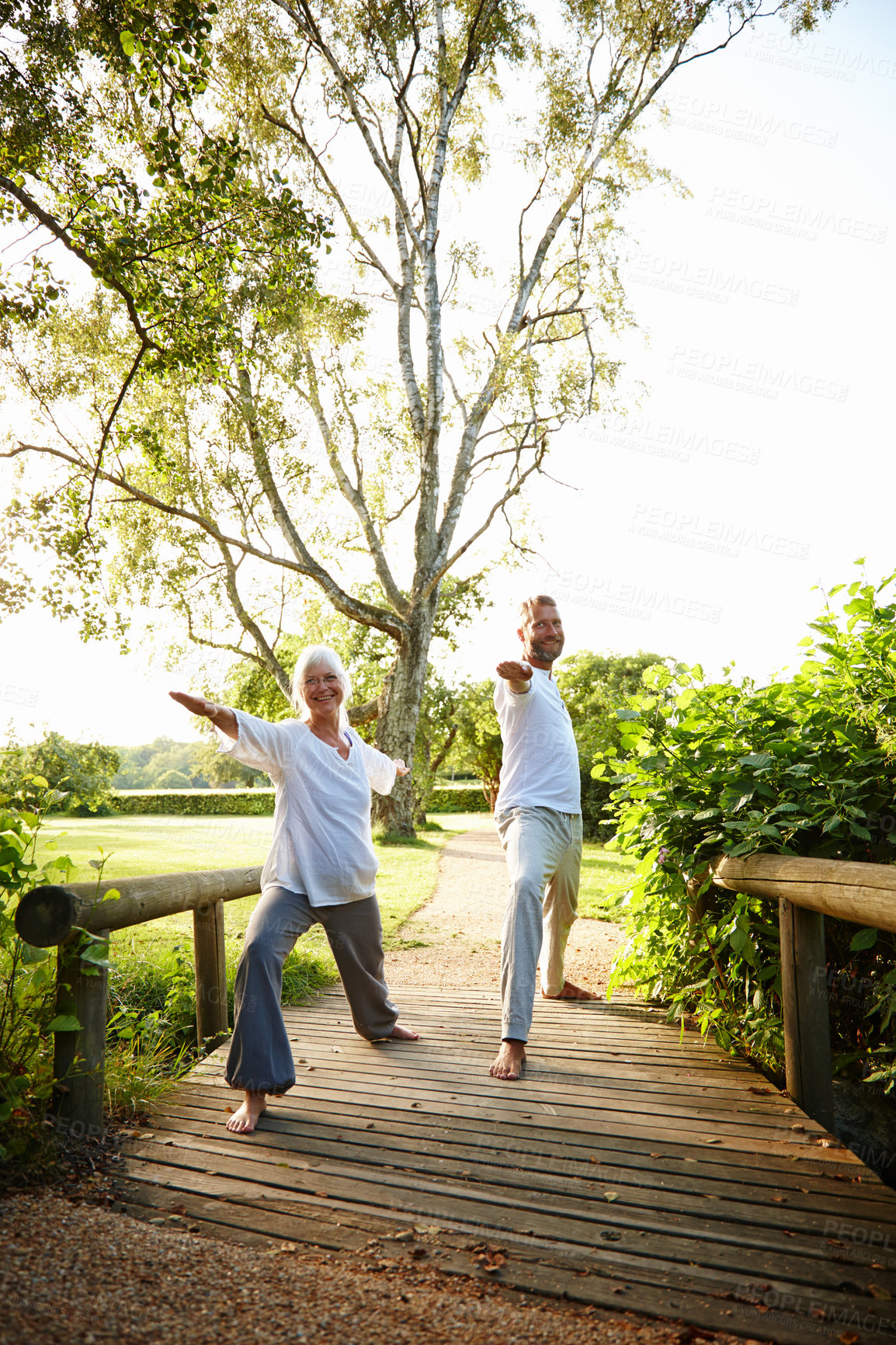 Buy stock photo Couple, stretching and happy with yoga in park for exercise, balance and mobility in nature. Bridge, mature people and warrior pose for arm workout, holistic wellness or training with pilates outdoor