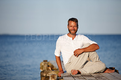 Buy stock photo Portrait of a handsome mature man doing yoga on a pier out on the ocean