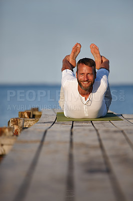 Buy stock photo Ocean, man and yoga with stretching on boardwalk for fitness, workout and exercise in German. Male person, outdoor and smile or happy on portrait with self care, wellness and health at seaside