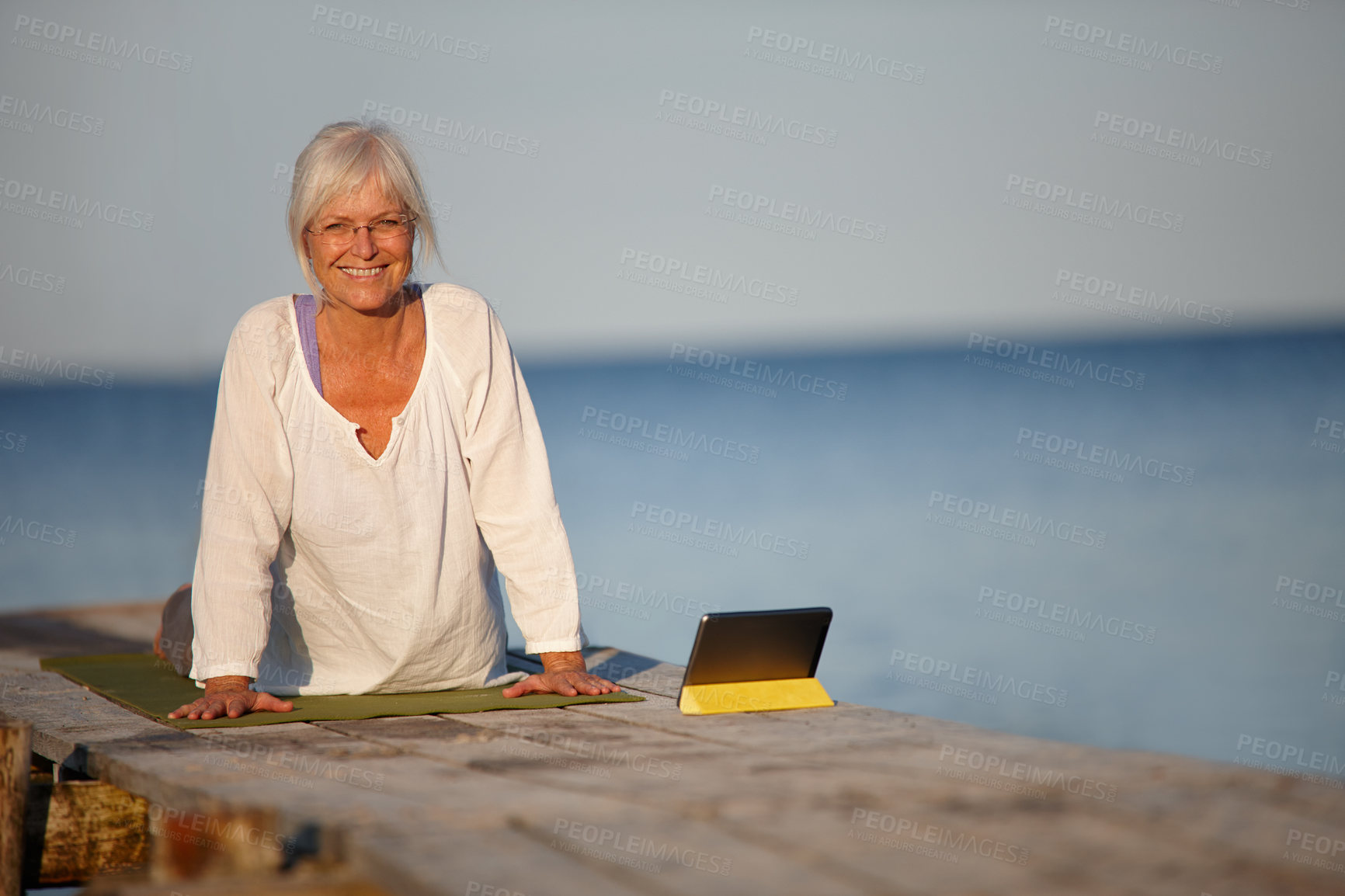 Buy stock photo Mature woman, portrait or yoga with tablet by lake for online tutorial, lesson or virtual class in nature. Senior, female person or yogi with smile for holistic training, workout or exercise by beach