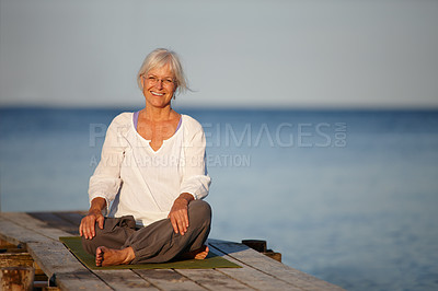 Buy stock photo Portrait of an attractive mature woman doing yoga on a pier out on the ocean