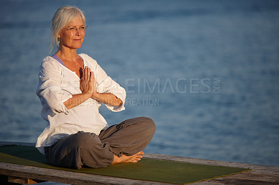 Buy stock photo Shot of an attractive mature woman doing yoga on a pier out on the ocean