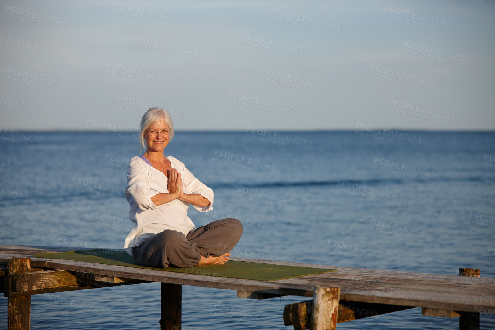 Buy stock photo Woman, portrait and meditation for yoga by ocean with holistic care, spiritual wellness and mindfulness. Mature person, namaste and pilates peace, mindset healing and performance for fitness outdoor