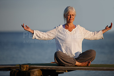 Buy stock photo Full length shot of an attractive mature woman doing yoga on a pier out on the ocean