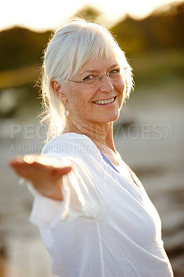 Buy stock photo Cropped portrait of an attractive mature woman doing yoga on the beach at sunset