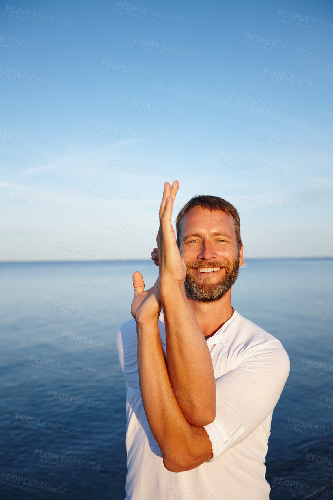 Buy stock photo Yoga, hands and portrait of man on beach with smile, health and wellness exercise in calm nature. Peace, stretching and person in eagle pose at ocean for fitness, balance and happy outdoor workout