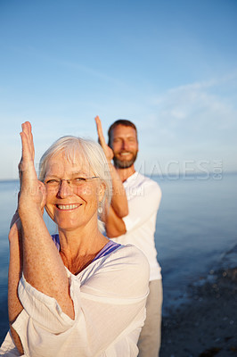 Buy stock photo Portrait, woman and man on beach for yoga with smile, health and wellness exercise in nature together. Team, stretching and mature people in eagle pose for fitness, balance and calm ocean workout