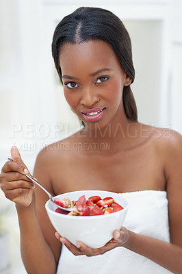 Buy stock photo Shot of a beautiful young woman eating a bowl of strawberries