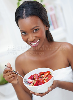 Buy stock photo Shot of a beautiful young woman eating a bowl of strawberries