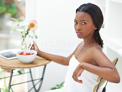 Buy stock photo Shot of a beautiful young woman eating a bowl of strawberries