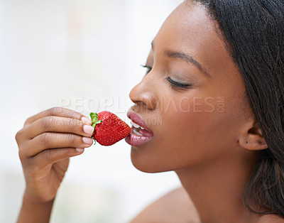 Buy stock photo Shot of a beautiful young woman eating strawberries