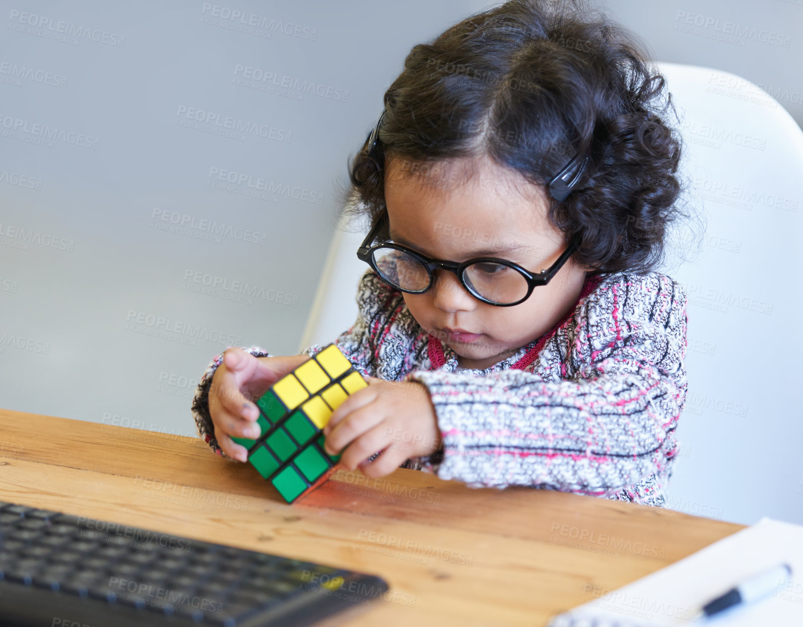 Buy stock photo Smart, rubix cube and a child for playing, learning and strategy with color at a desk. House, clever and a girl, young kid and a baby with toys for thinking, psychology development and a solution