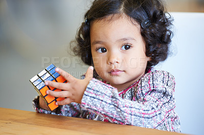 Buy stock photo Portrait, game and a child with a rubix cube for playing, learning and education in a house. Young, desk and a girl, kid or baby with toys for a solution, strategy or color search for psychology