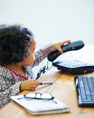 Buy stock photo Playing, child and a telephone for a phone call at a desk for communication, pretend work or childhood. Playful, table and a girl, kid or baby with a landline for conversation, contact or secretary