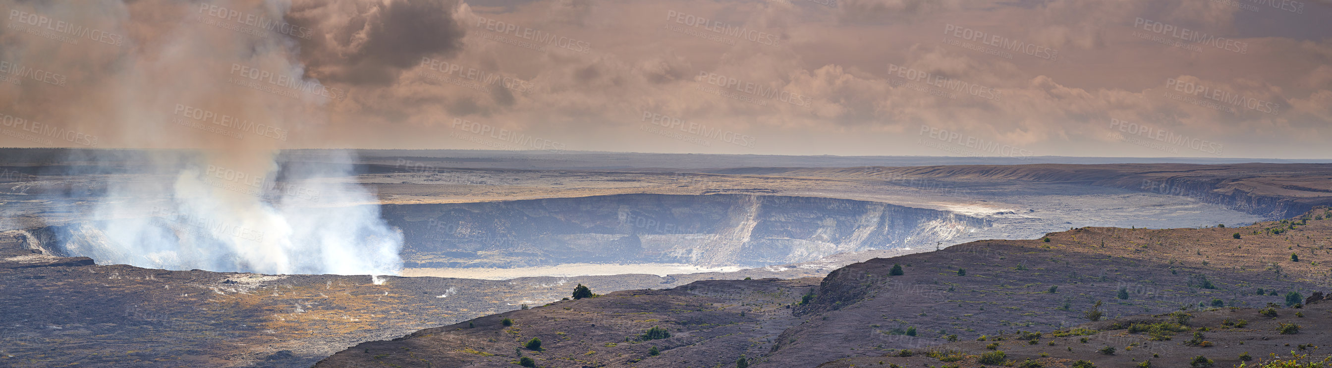 Buy stock photo Mouna Kea most active volcano on a cloudy day. Extreme panoramic landscape of Hawaiian mountain with green fields in foreground. Overcast skies reveal the small steaming volcano in the background