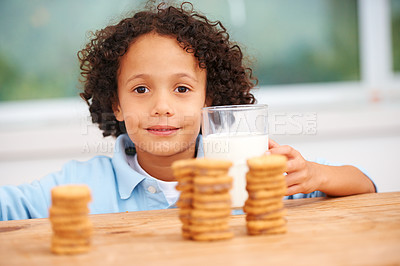 Buy stock photo Milk, cookies and portrait of boy child by the kitchen counter eating a sweet snack or treat at home. Smile, dessert and hungry young kid enjoying biscuits by a wooden table in a modern family house.