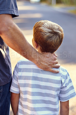 Buy stock photo Rearview shot of a father and son walking down the street together