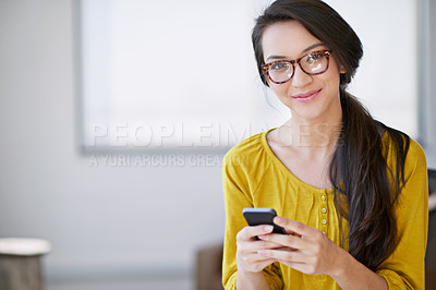 Buy stock photo Shot of an attractive young woman using a cellphone in an office