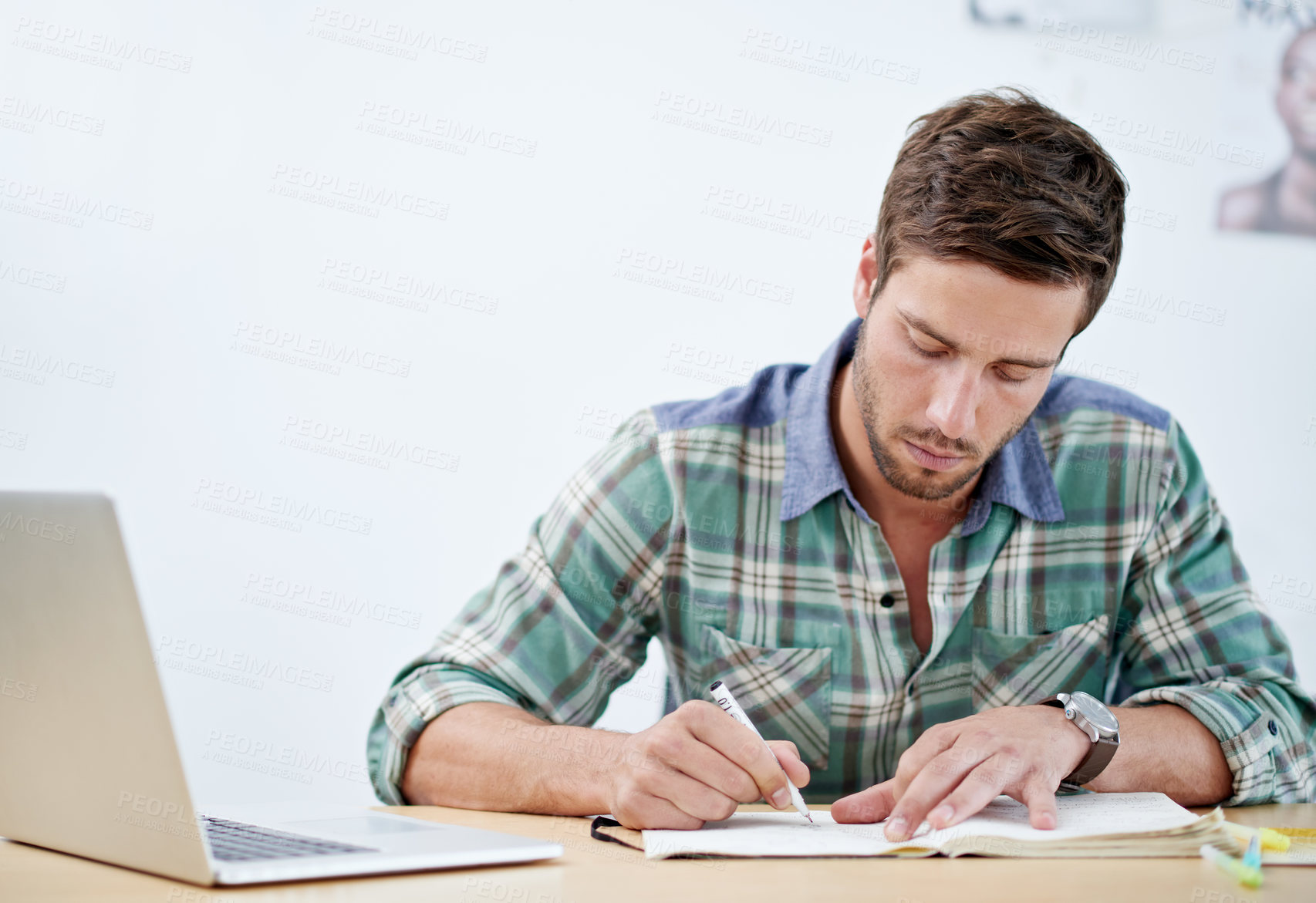 Buy stock photo Shot of a casually-dressed young man using a digital tablet at his desk. The commercial designs displayed  represent a simulation of a real product and have been changed or altered enough by our team of retouching and design specialists so that they don't have copyright infringements