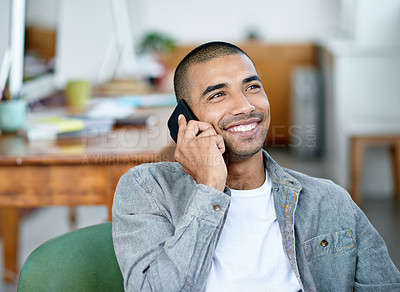 Buy stock photo Shot of a handsome young office worker talking on a cellphone while sitting in an office