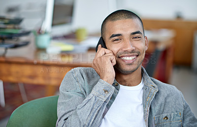 Buy stock photo Portrait of a handsome young office worker talking on a cellphone while sitting in an office