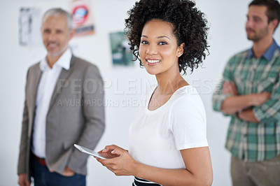 Buy stock photo Portrait of an attractive young businesswoman using a digital tablet with her colleagues in the background. The commercial designs displayed  represent a simulation of a real product and have been changed or altered enough by our team of retouching and design specialists so that they don't have copyright infringements