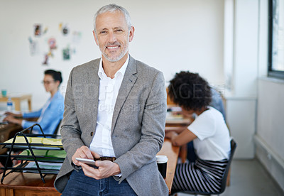 Buy stock photo Portrait of a mature businessman using a cellphone while sitting on a table in an office