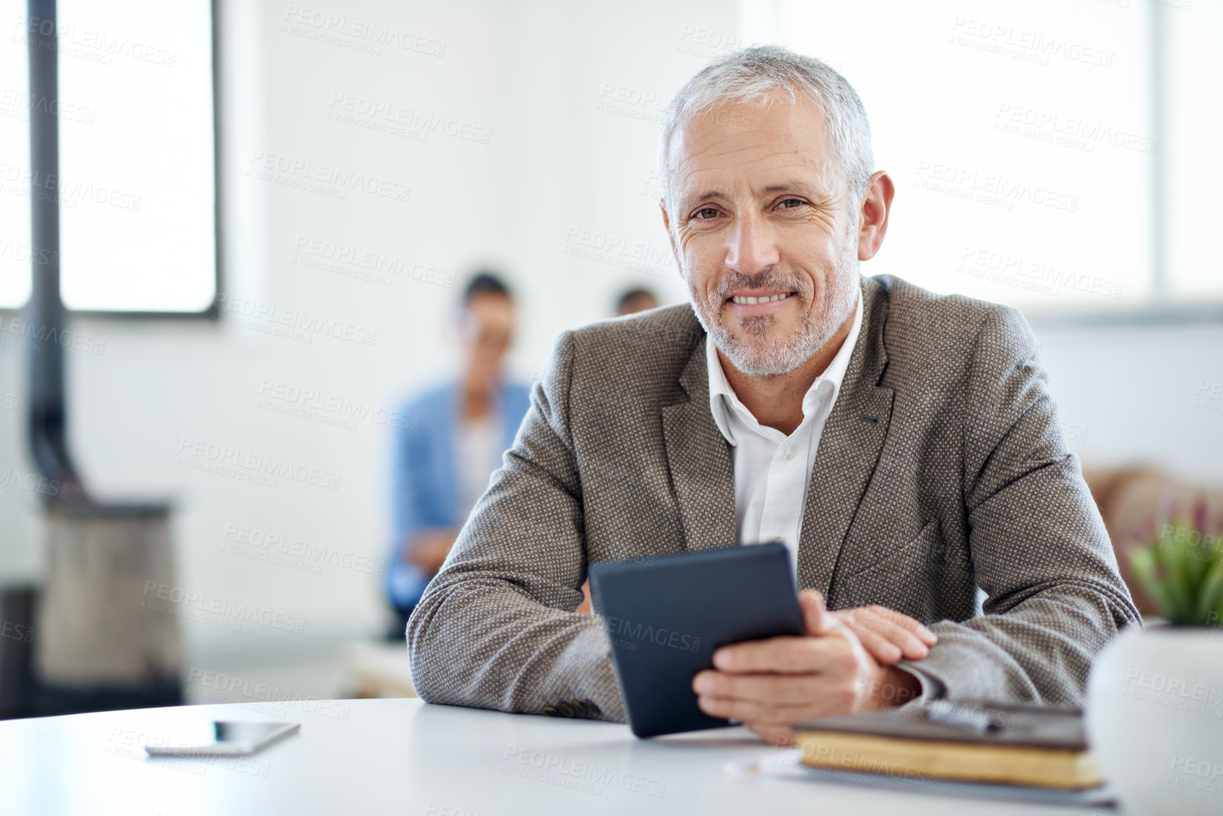 Buy stock photo Portrait of a mature businessman using a digital tablet while sitting at a table in an office