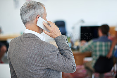 Buy stock photo Shot of a mature businessman talking on a cellphone while standing in an office