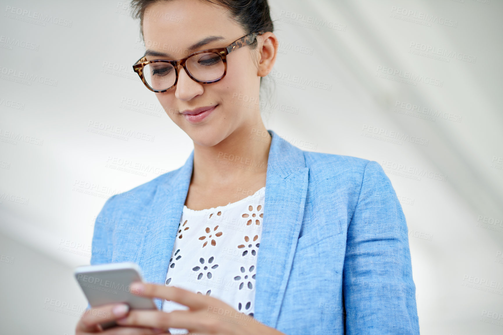 Buy stock photo Shot of an attractive young woman using a cellphone in an office