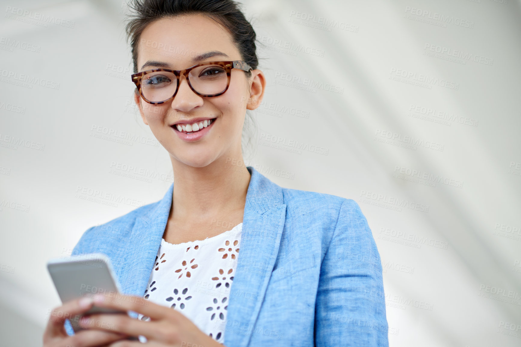 Buy stock photo Shot of an attractive young woman using a cellphone in an office
