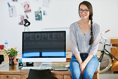 Buy stock photo Portrait of an attractive young woman sitting on her desk at work. The commercial designs displayed  represent a simulation of a real product and have been changed or altered enough by our team of retouching and design specialists so that they don't have copyright infringements