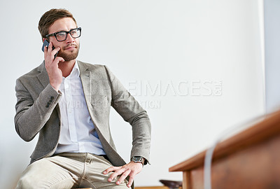 Buy stock photo Shot of a handsome businessman talking on his cellphone in the office