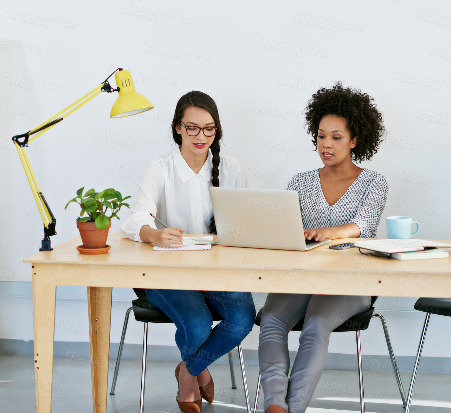Buy stock photo Shot of two young businesswomen working on a laptop