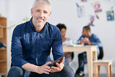 Buy stock photo Portrait of a handsome businessman using a digital tablet in the office. The commercial designs displayed  represent a simulation of a real product and have been changed or altered enough by our team of retouching and design specialists so that they don't have copyright infringements