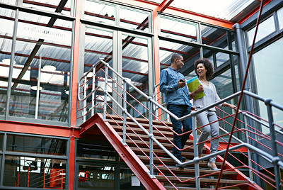 Buy stock photo Two colleagues walking side by side down stairs in their building