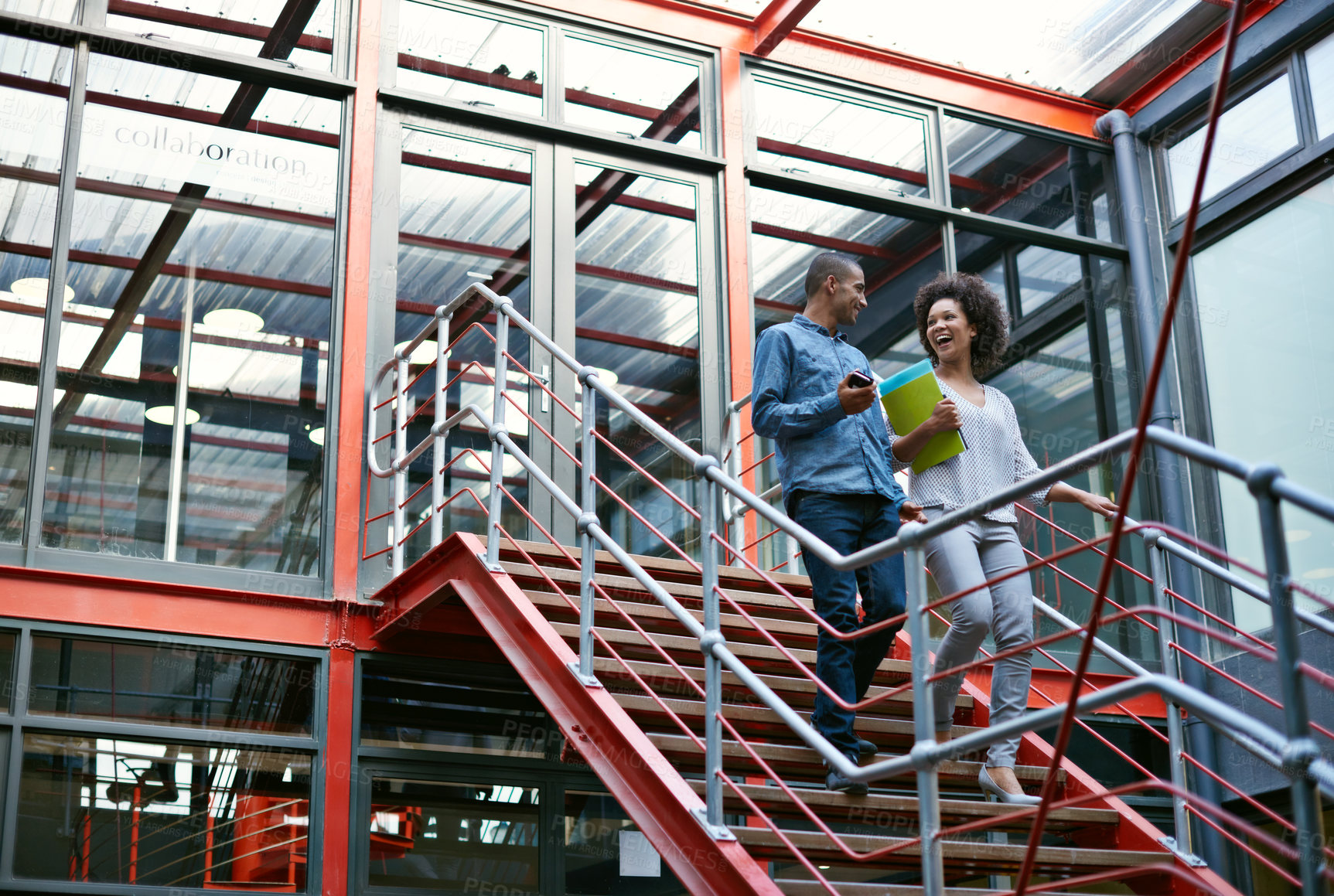 Buy stock photo Two colleagues walking side by side down stairs in their building