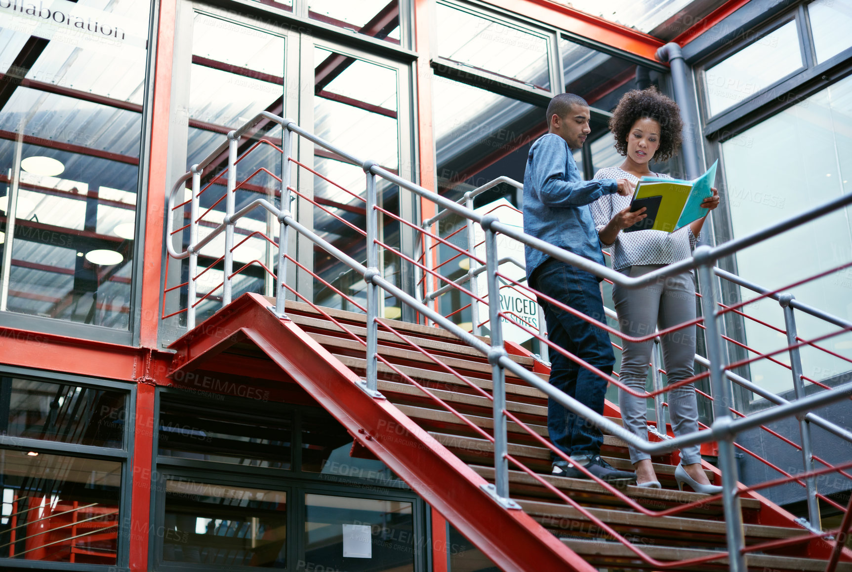 Buy stock photo Two colleagues walking side by side down stairs in their building