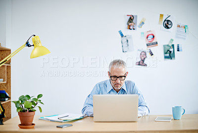 Buy stock photo Shot of a handsome businessman working on his laptop. The commercial designs displayed represent a simulation of a real product and have been changed or altered enough by our team of retouching and design specialists so that they don't have copyright infringements