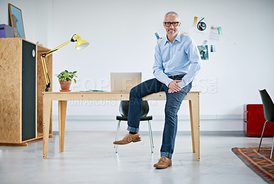 Buy stock photo Portrait of a handsome businessman sitting on his desk. The commercial designs displayed represent a simulation of a real product and have been changed or altered enough by our team of retouching and design specialists so that they don't have copyright infringements