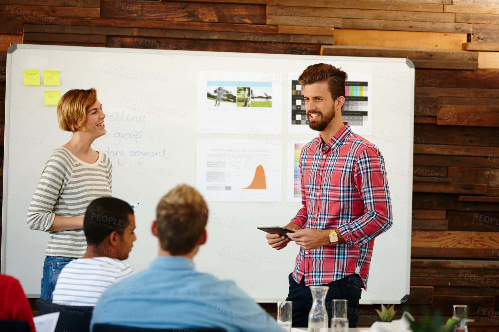 Buy stock photo Shot of a group of young designers having a brainstorming meeting at a whiteboard