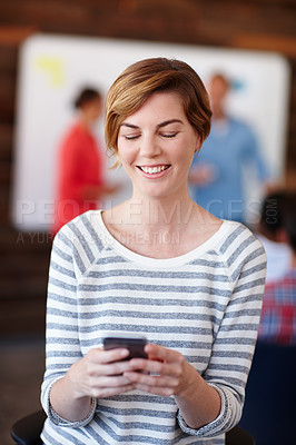 Buy stock photo Shot of a young female designer using her cellphone at work