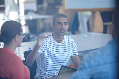 Buy stock photo Through the glass shot of a group of designers discussing ideas in a meeting