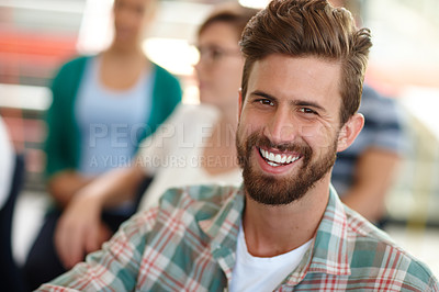 Buy stock photo Shot of a male designer smiling at the camera with his colleagues in the background