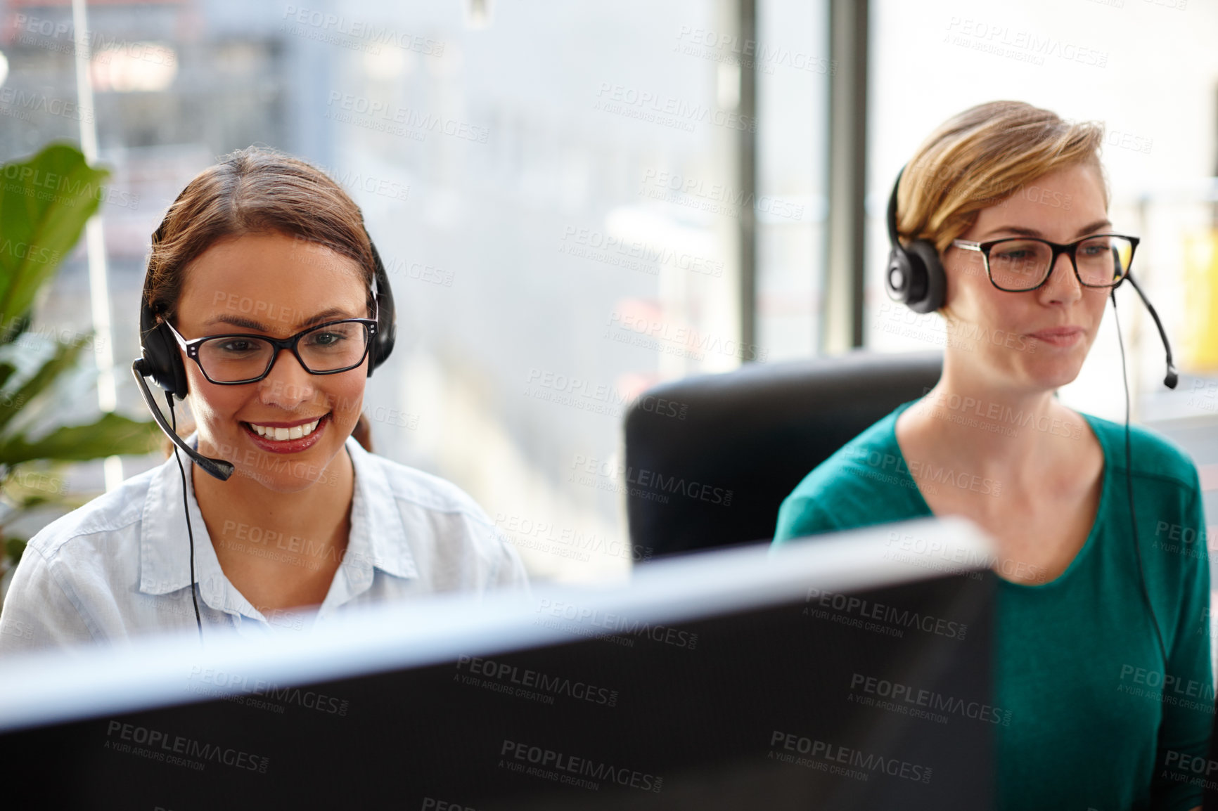 Buy stock photo Shot of two female customer service representatives taking calls in their office