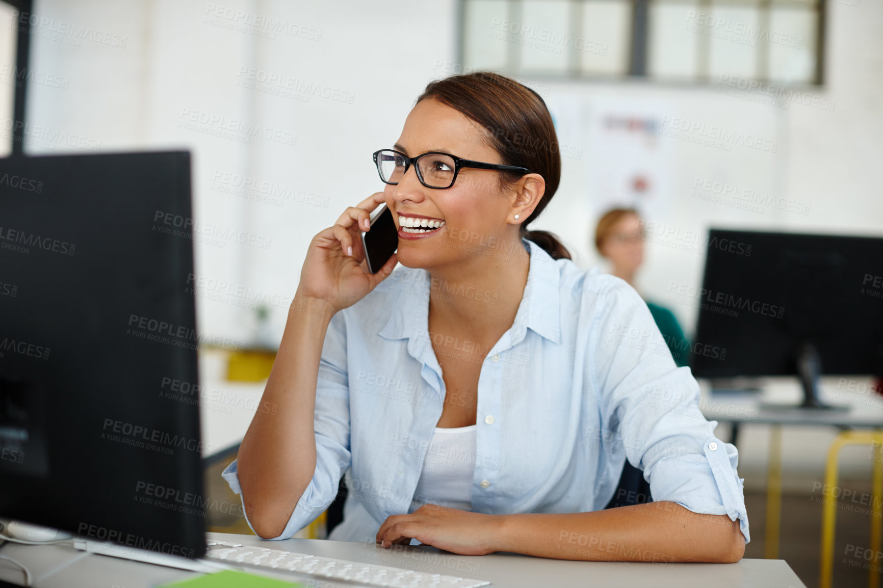 Buy stock photo Shot of a young female designer talking on the phone while sitting at her desk